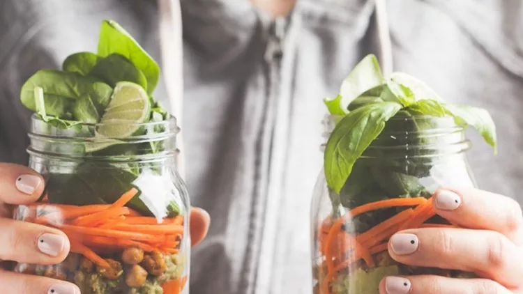woman-holds-and-eats-a-salad-in-a-glass-jar-with-baked-chickpeas-and-picture-id918079594