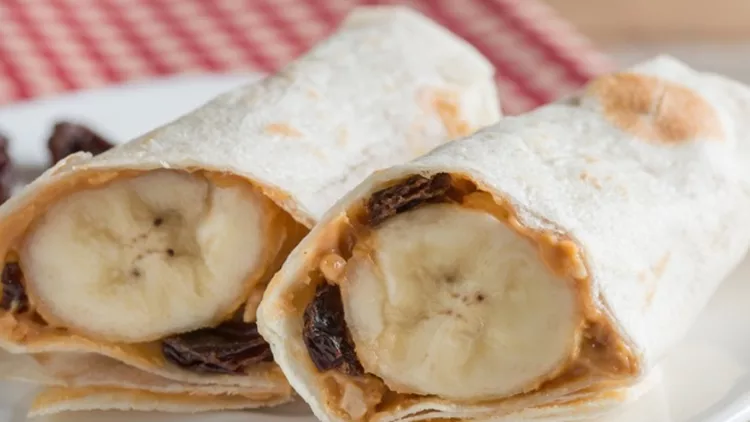 slice-tortilla-wrap-with-peanut-butter-raisin-and-banana-picture-id546772730