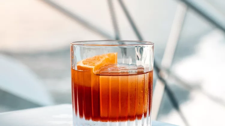 negroni-cocktail-with-big-ice-cube-on-a-boat-at-sunset-picture-id1198420810