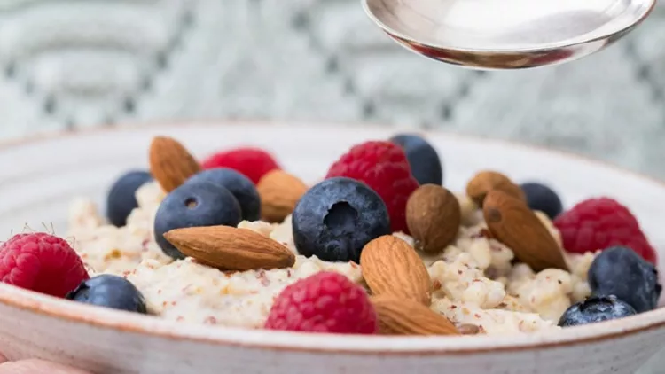 close-up-of-woman-eating-bowl-of-porridge-with-fruit-and-nuts-for-picture-id927961622