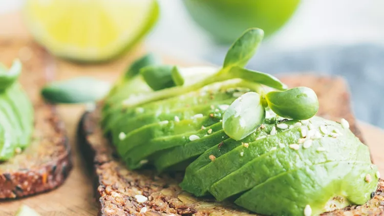 two-toasts-with-avocado-on-a-wooden-board-on-a-breakfast-table-the-picture-id1077286358