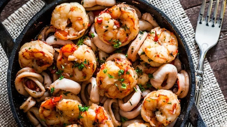 shrimps-and-calamari-rings-cooked-on-iron-cast-pan-picture-id863505818