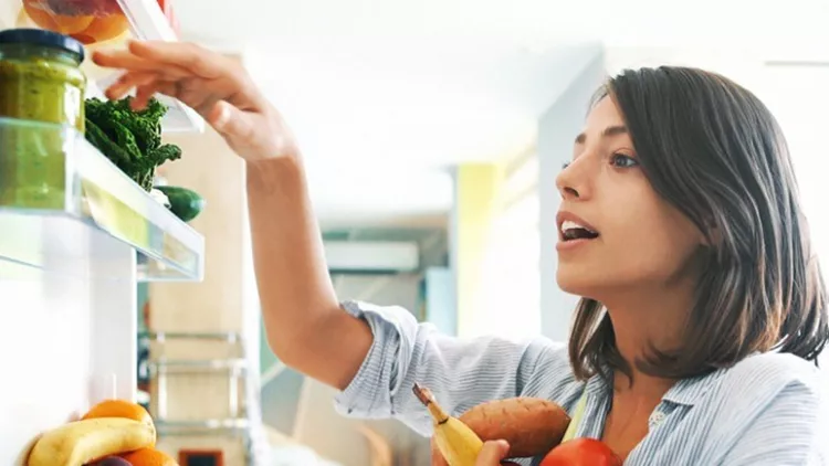 woman-picking-up-some-fruits-and-veggies-from-the-fridge-picture-id1024069556