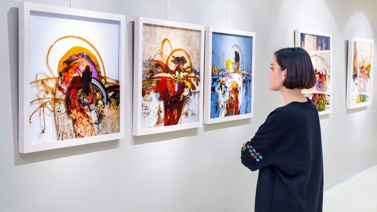 γυναίκα μπροστά σε πίνακες για εικαστική ψυχοθεραπεία