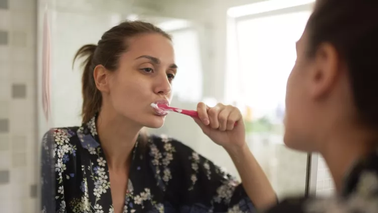 Γυναίκα που βουρτσίζει τα δόντια της στο μπάνιο